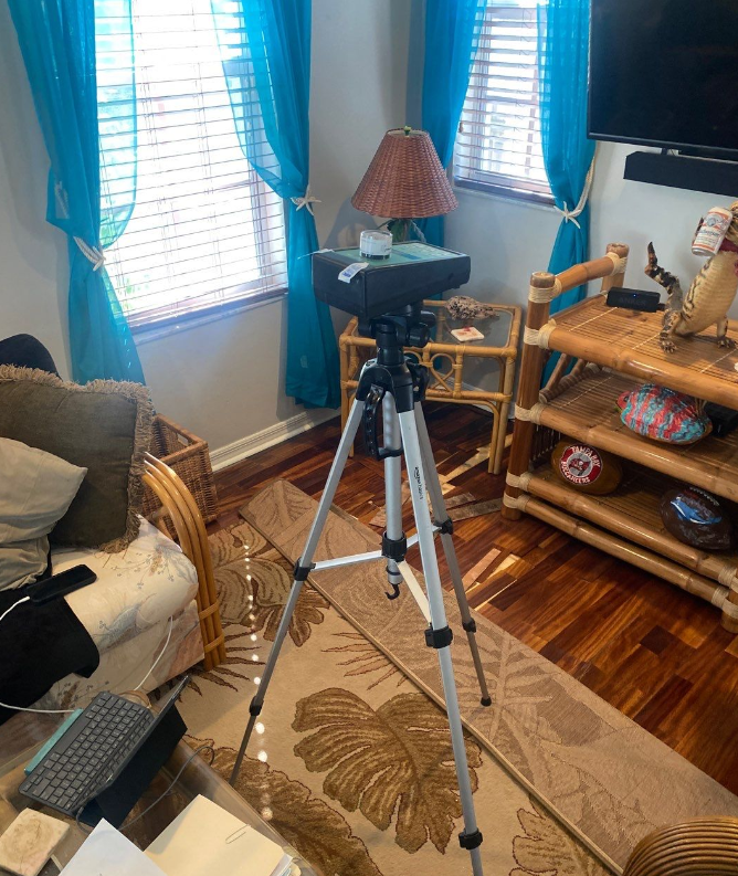 A camera on a tripod in a living room with blue curtains