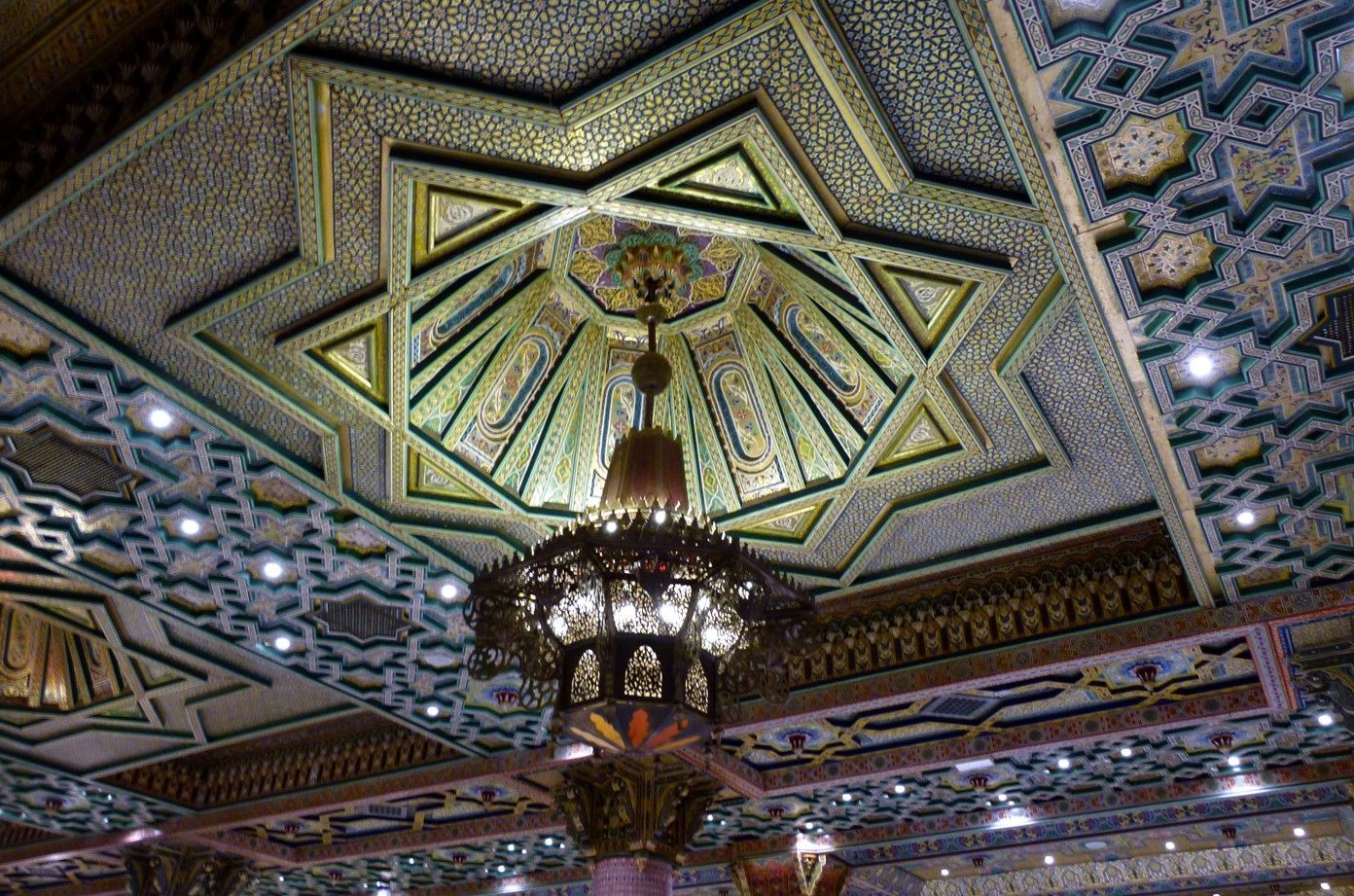 Een sierlijk, geometrisch plafond met een sterrenmotief en een kroonluchter.
