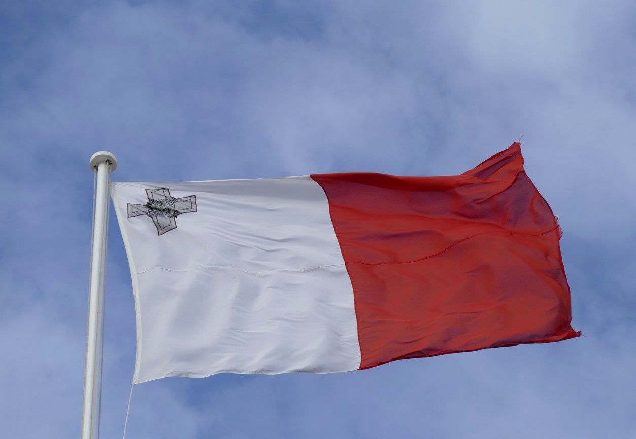 Vlag van Malta: witte en rode verticale helften, het Georgeskruis-embleem linksboven, wapperend in de wind.