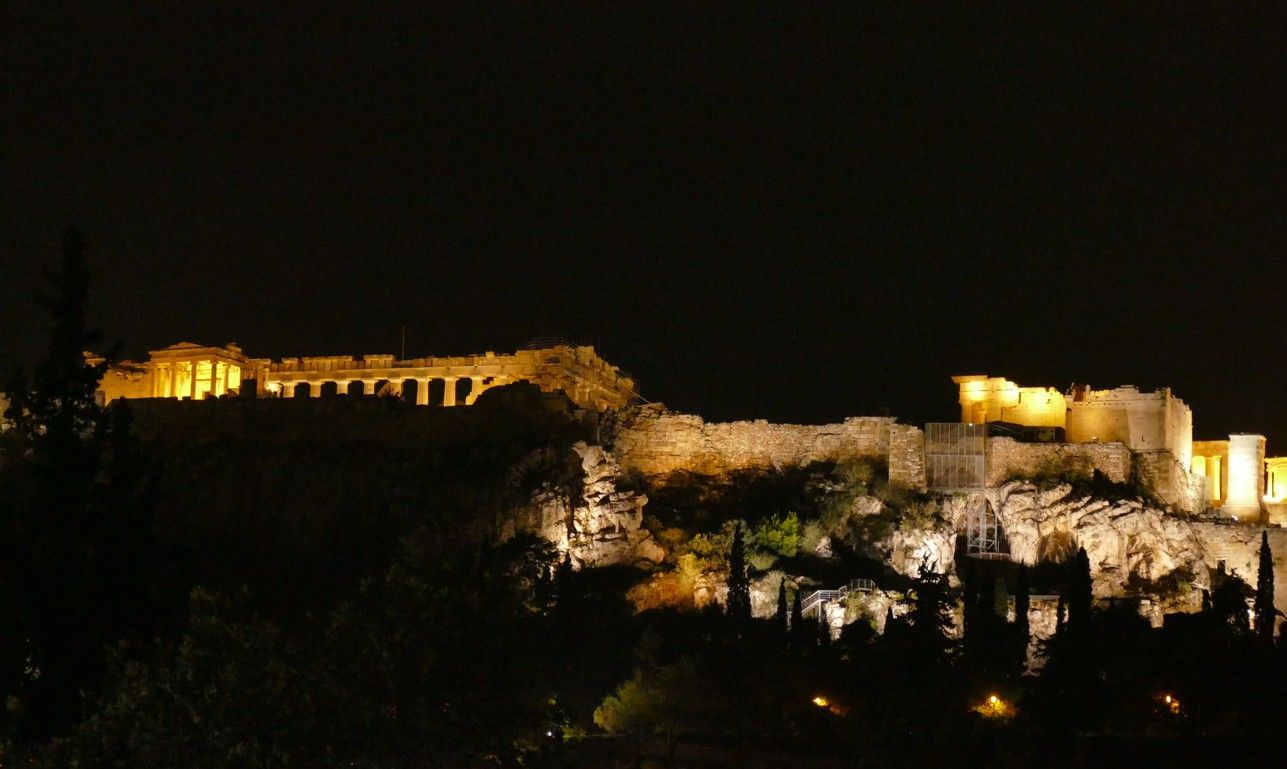 Nachtzicht op de verlichte Akropolis in Athene, Griekenland, met gouden lichtjes tegen een donkere hemel.