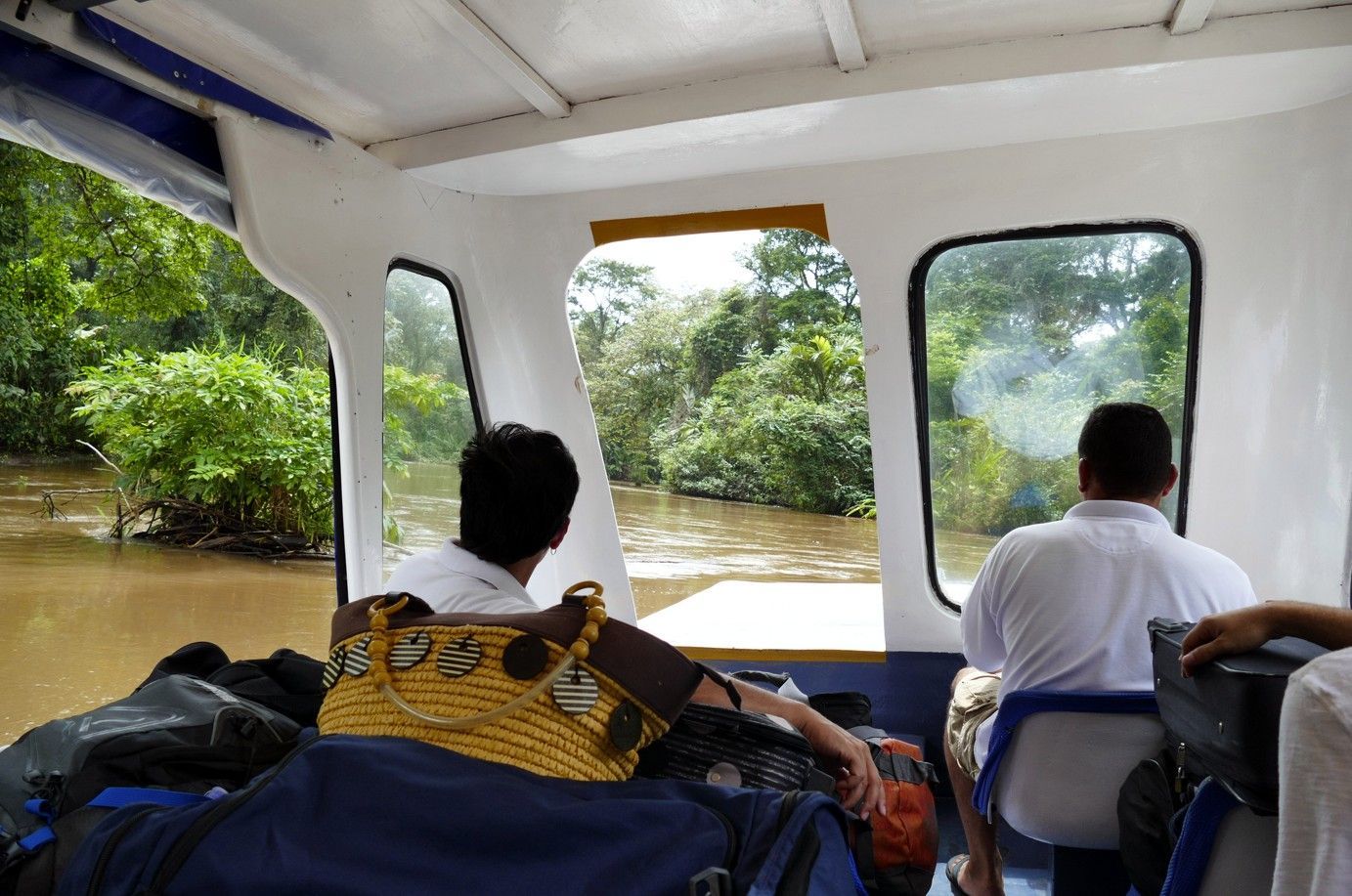 In een boot kijken twee mensen door de ramen naar een ondergelopen, groen landschap.