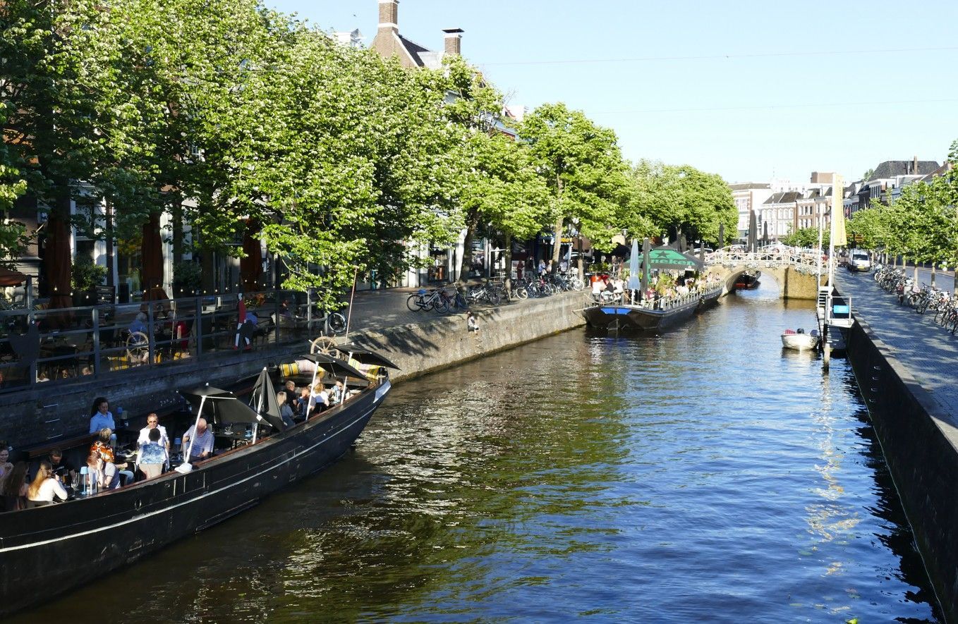 Grachten met boten en bomen in Amsterdam op een zonnige dag.