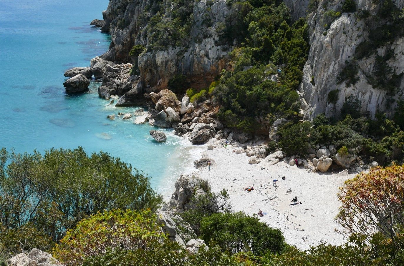Rotsachtige kustlijn met turquoise water en een klein strandje.