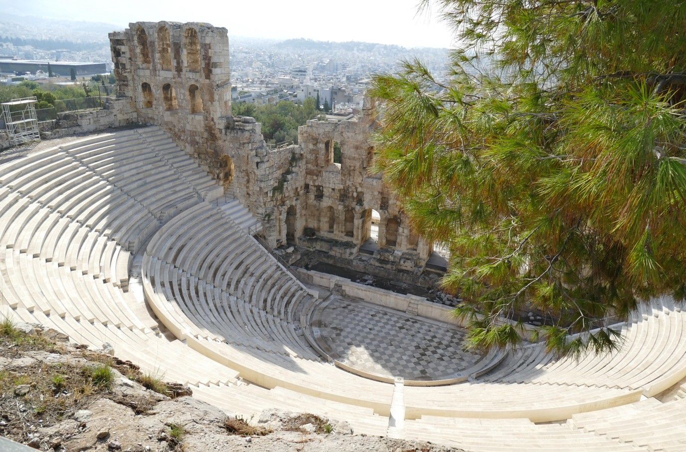 Stenen amfitheater met tribune, onderdeel van een oude bouwruïne in Athene, Griekenland, met de stad op de achtergrond.