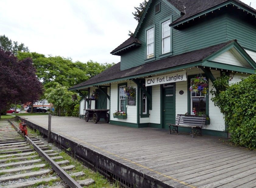 Het groen-witte treinstation van Fort Langley met een bakstenen perron en sporen.