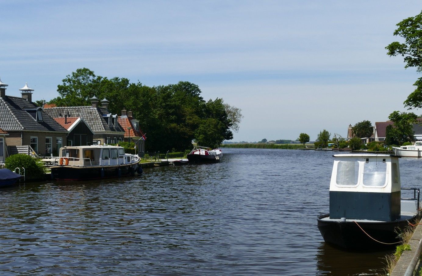 Een kanaal met boten en huizen langs de oevers onder een blauwe hemel.