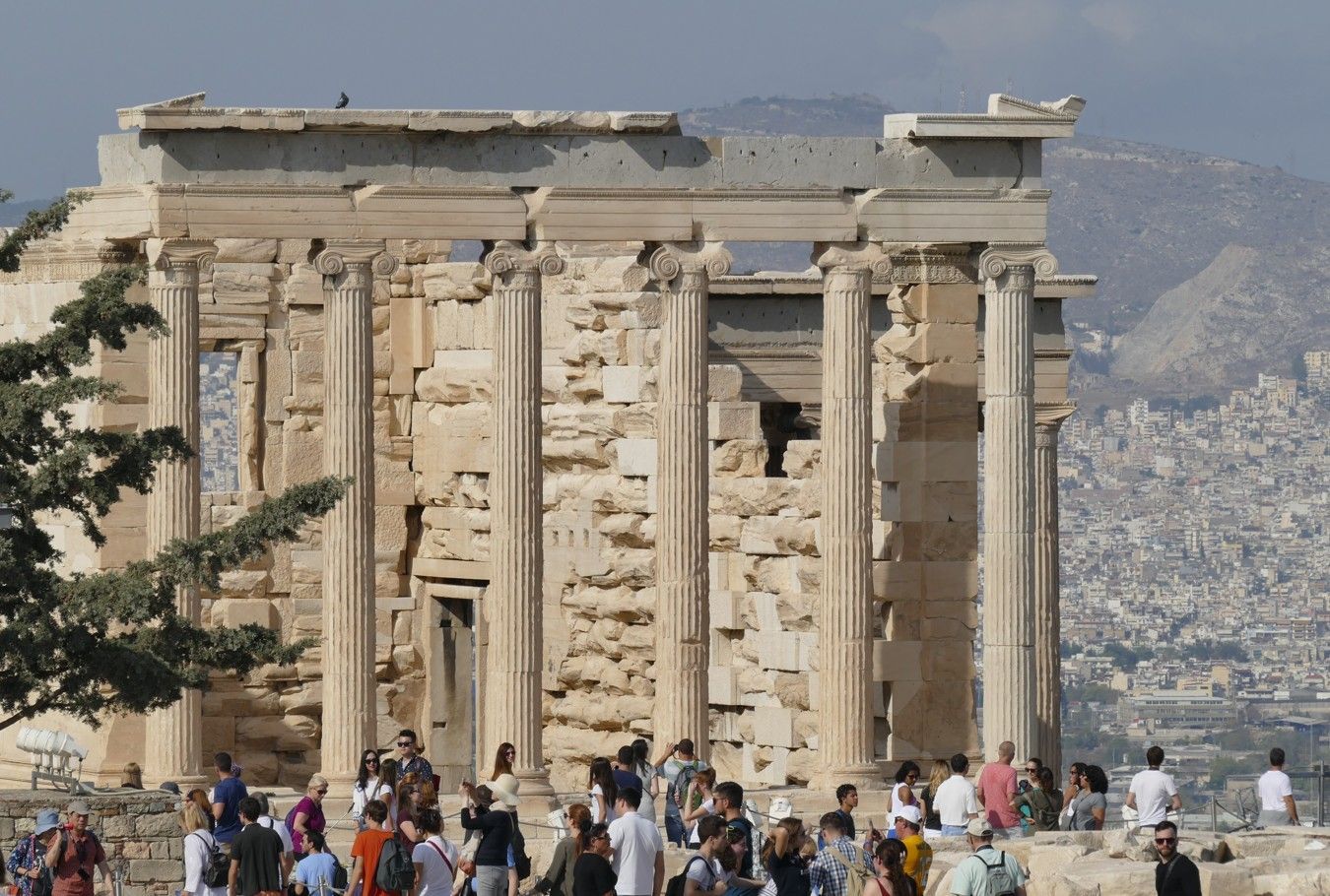 Oude Griekse tempel op een heuveltop, met zuilen, gedeeltelijk in ruïne, en veel toeristen in Athene.