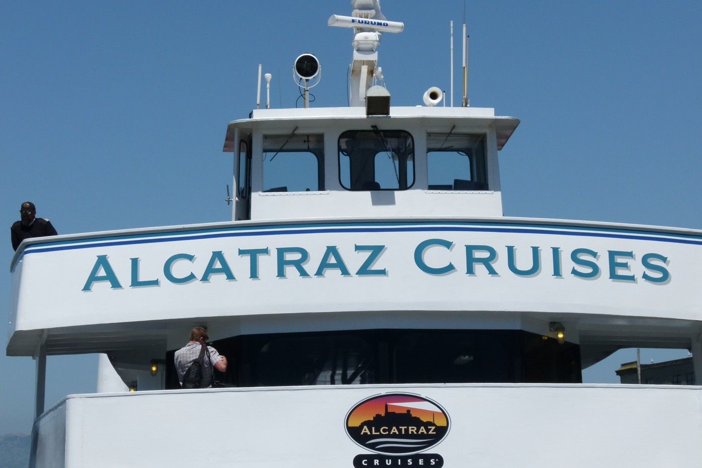 De veerboot van Alcatraz Cruises met blauw-witte letters en logo op een zonnige dag.
