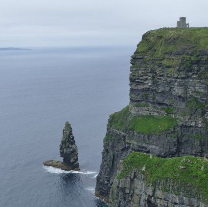 De kliffen van Moher in Ierland, groen gras, stenen toren, oceaan, bewolkte lucht.