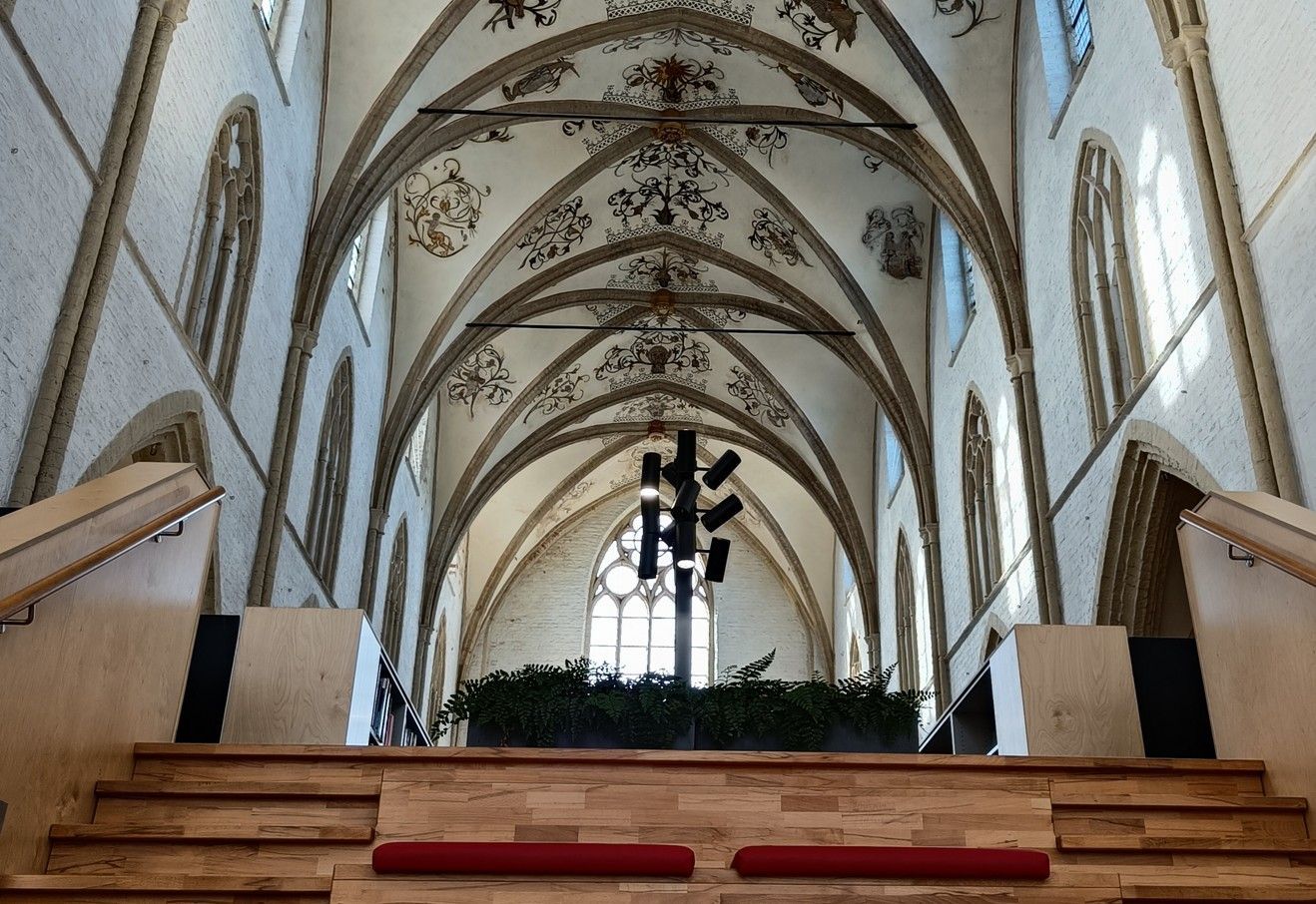 Interieurfoto van een kerk met een gewelfd plafond, boogvensters en een verhoogd podium.