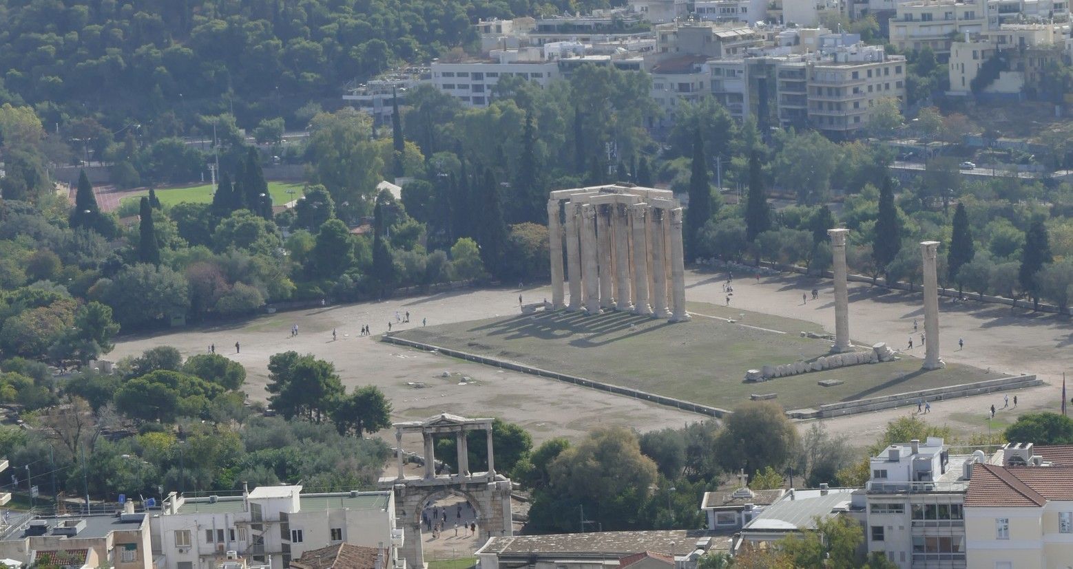 Ruïnes van de tempel van de Olympische Zeus in Athene, Griekenland, met nog overeind staande zuilen en omringend groen.
