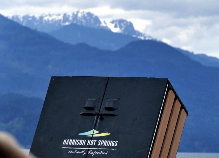 Bord met de aanduiding Harrison Hot Springs en bergen op de achtergrond.