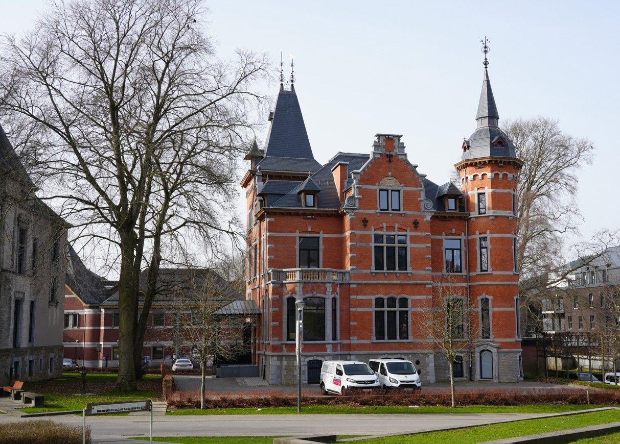Een herenhuis , opgetrokken uit rode baksteen, met een torentje, een steil leien dak en witte stenen accenten.
