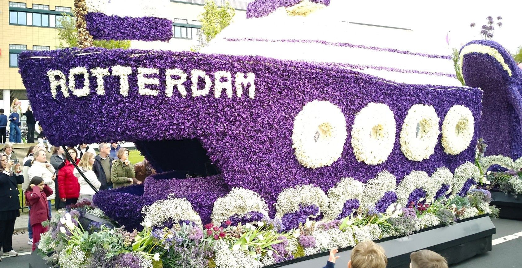Paarse praalwagen met bloemenmotief, met het opschrift 