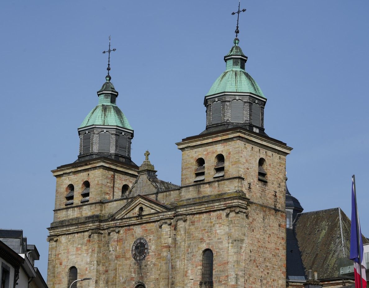 Onder een helderblauwe hemel verrijzen twee torens met groen gepatineerde koperen koepels van een oude Europese kerk.
