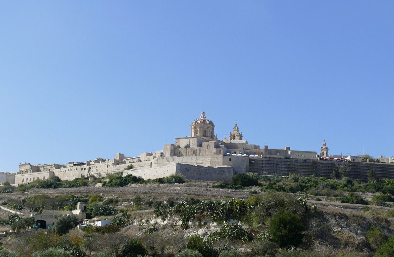 De historische ommuurde stad Mdina op Malta, gelegen op een heuvel, met stenen gebouwen en een blauwe hemel.