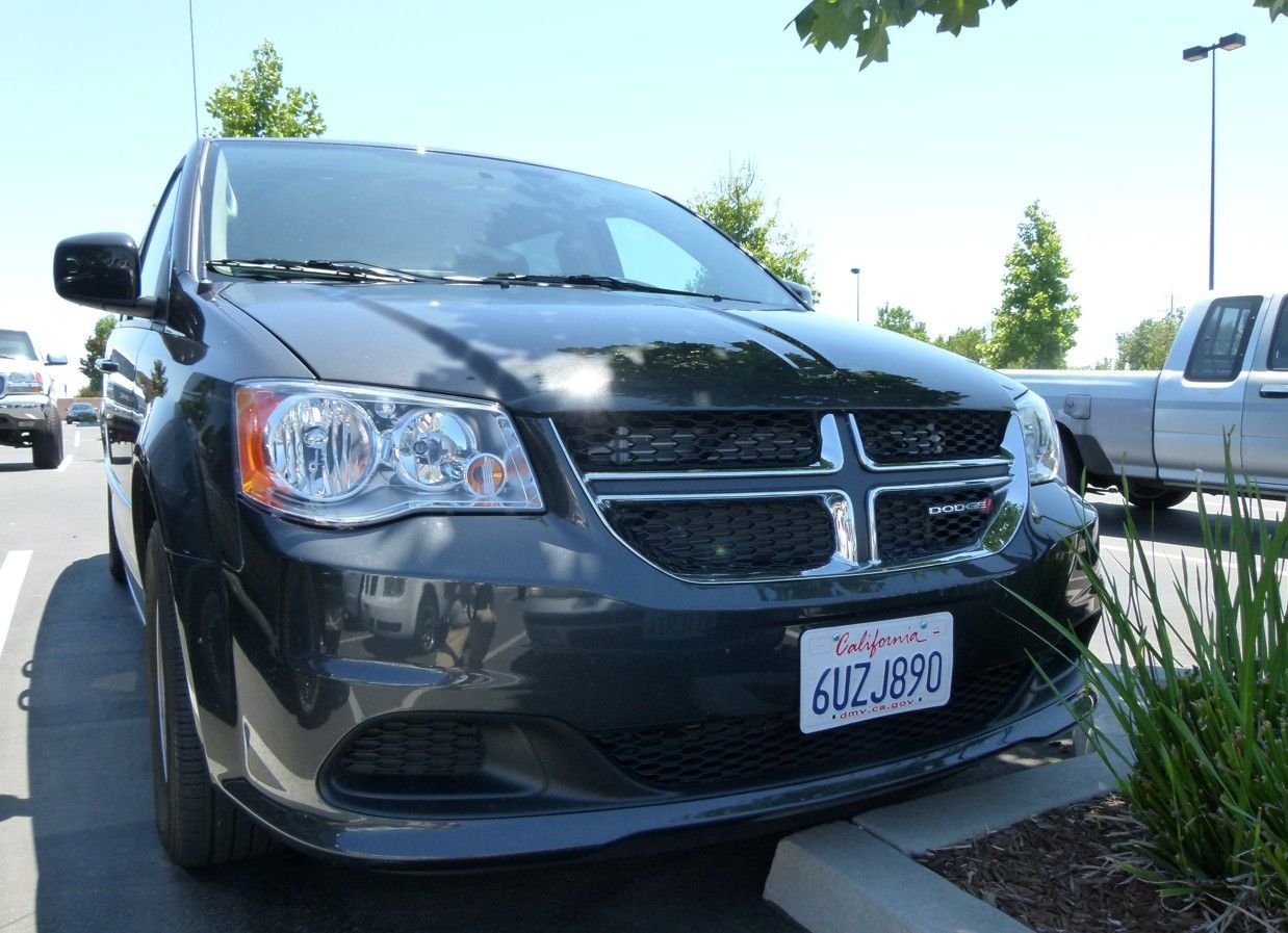 Donkergrijze Dodge Grand Caravan geparkeerd op een parkeerplaats; Californisch kenteken.