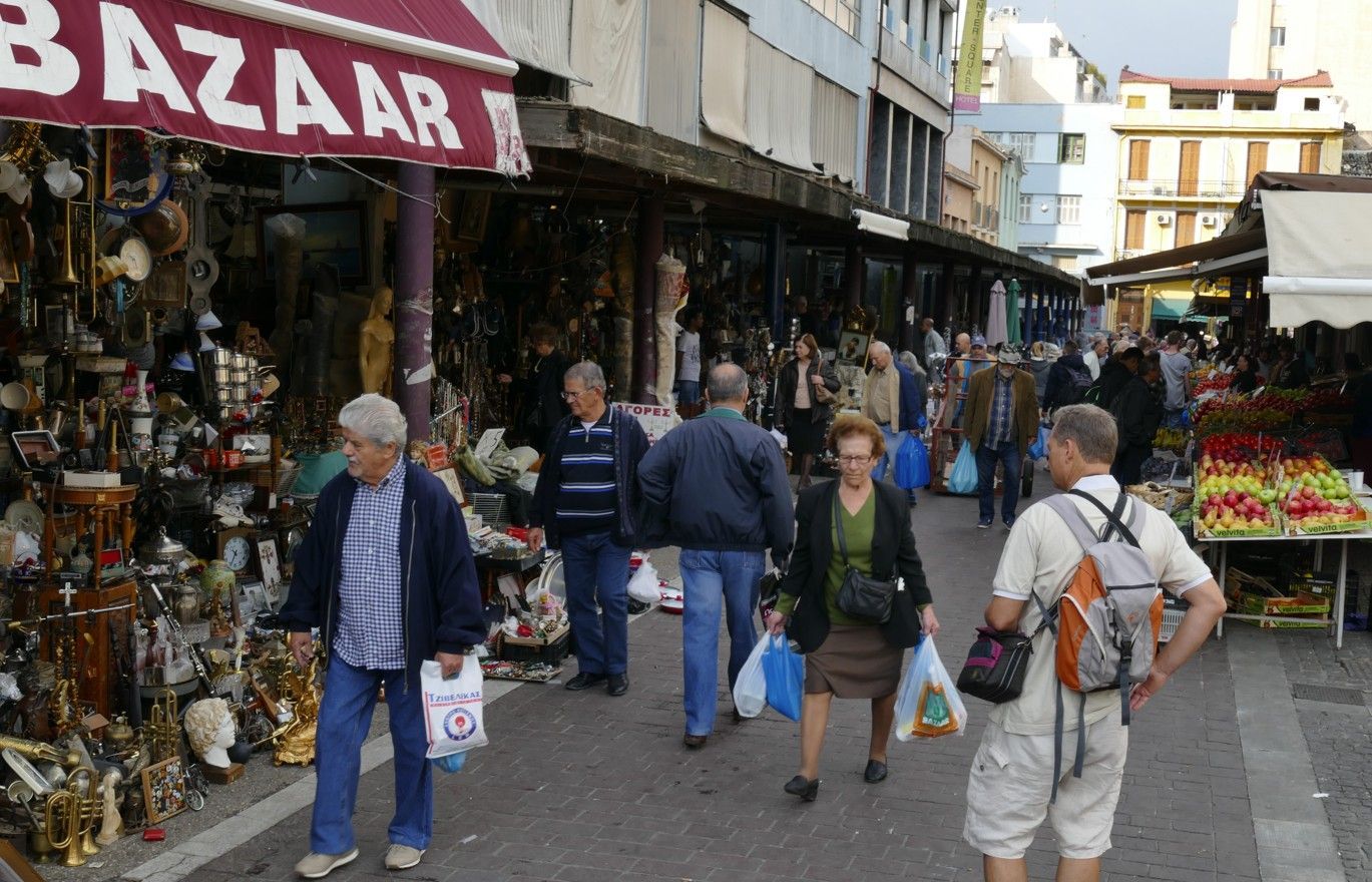 Een bazaar vol winkelend publiek, winkels die uitpuilen van de koopwaar en mensen die voorbijlopen.