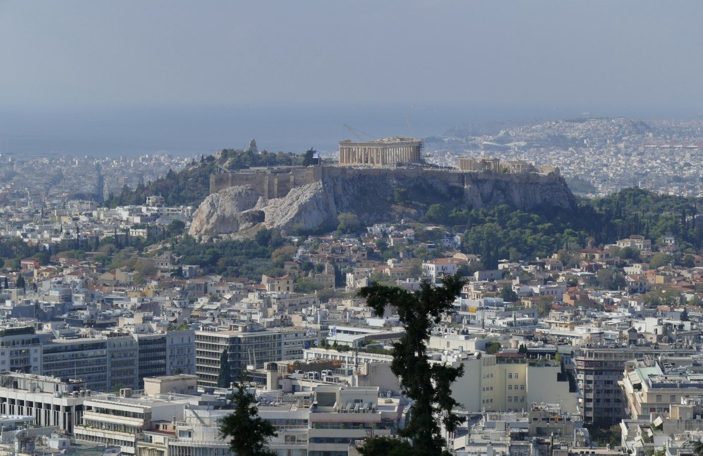 De Akropolis in Athene, Griekenland, bovenop een heuvel, omgeven door een stadslandschap onder een heldere hemel.