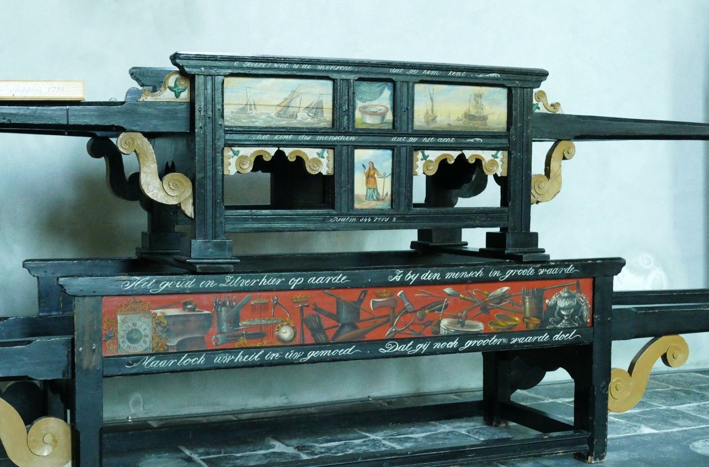 Een zwart-gouden baar met beschilderde taferelen en tekst, waarop kunst in een kerk tentoongesteld wordt.