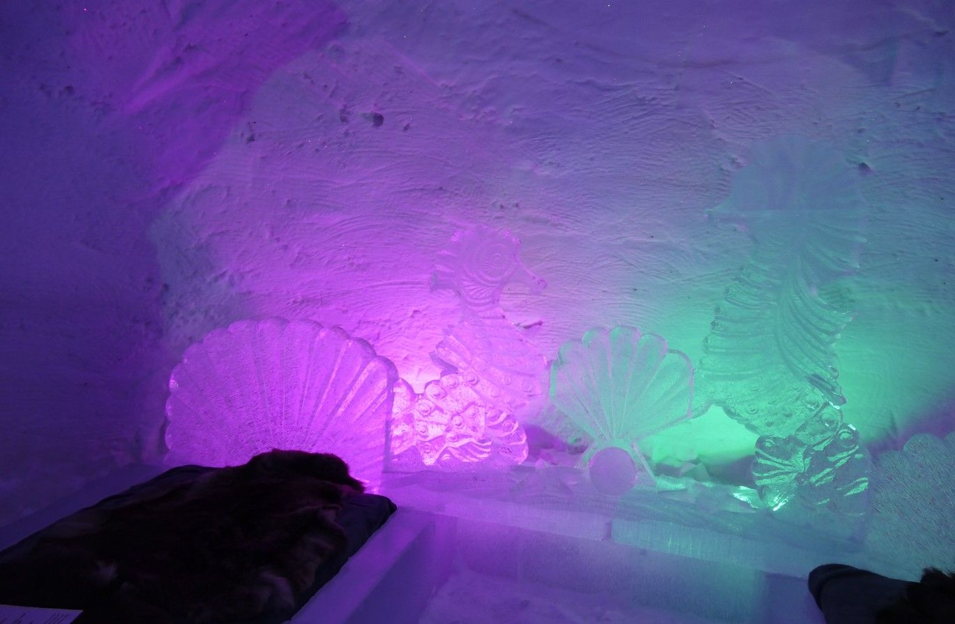 Paarse en groene lichten verlichten het interieur van een ijsgrot en laten de ijsformaties zien.