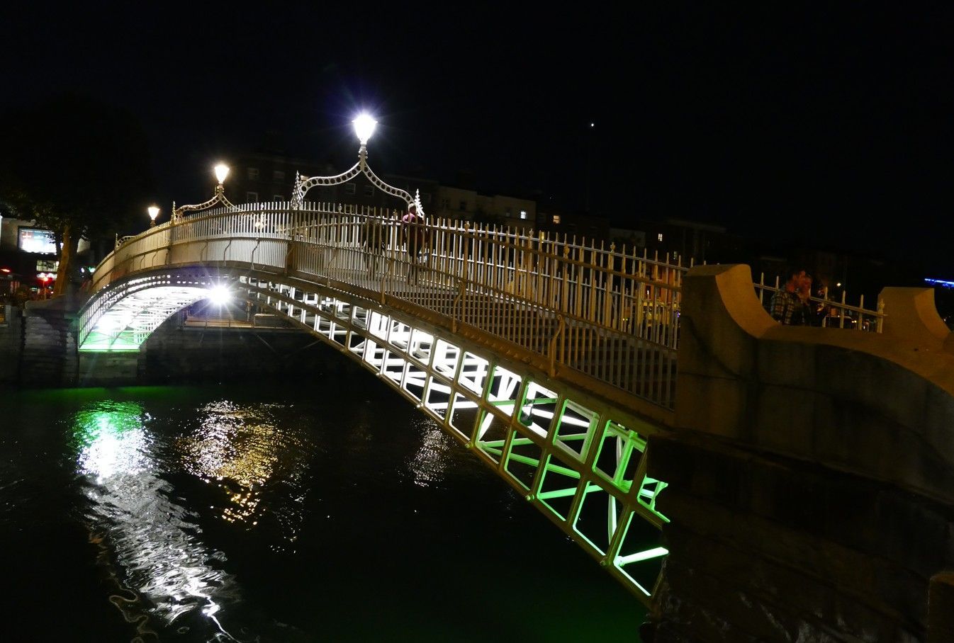 Nachtzicht op de verlichte Ha'penny Bridge in Dublin, Ierland, die weerspiegelt in het donkere water.