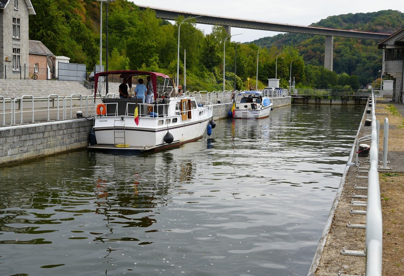 Boten liggen aangemeerd langs een rustig kanaal naast stenen muren en een brug op een heuvel.