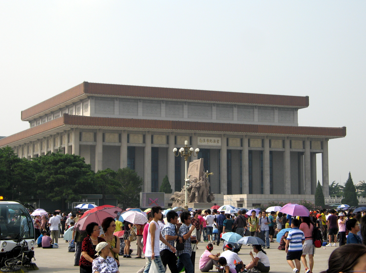 Mausoleum met grote menigte op het Tiananmenplein. Mensen houden paraplu's vast.