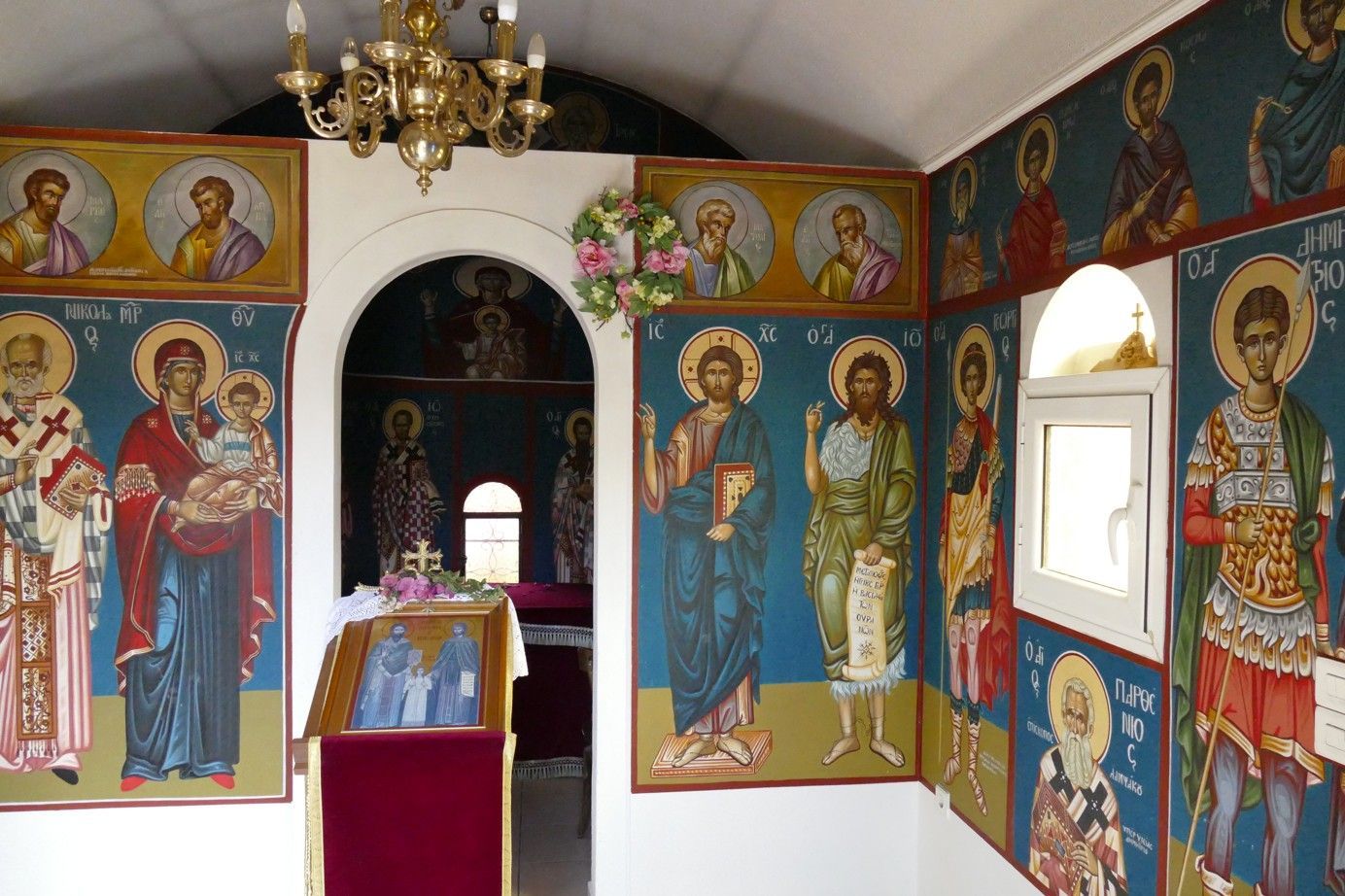 Interieur van een orthodoxe kerk, muren versierd met religieuze iconen in levendige kleuren.