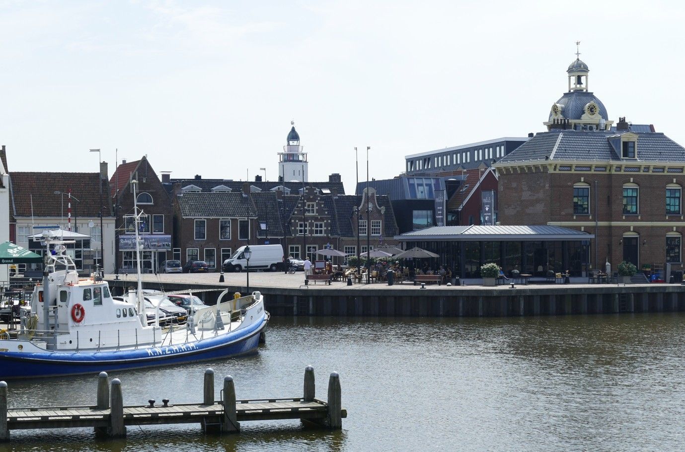 Havengezicht met een witte boot, oude gebouwen en een koepelvormig bouwwerk op een zonnige dag.
