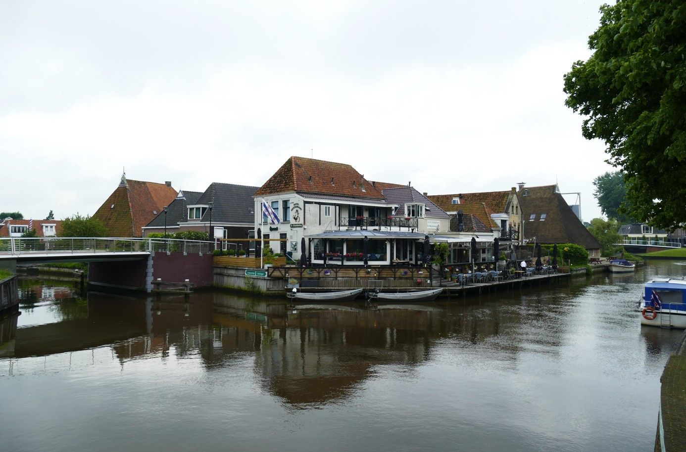 Gebouwen aan het water met een brug en boten, onder een bewolkte hemel.