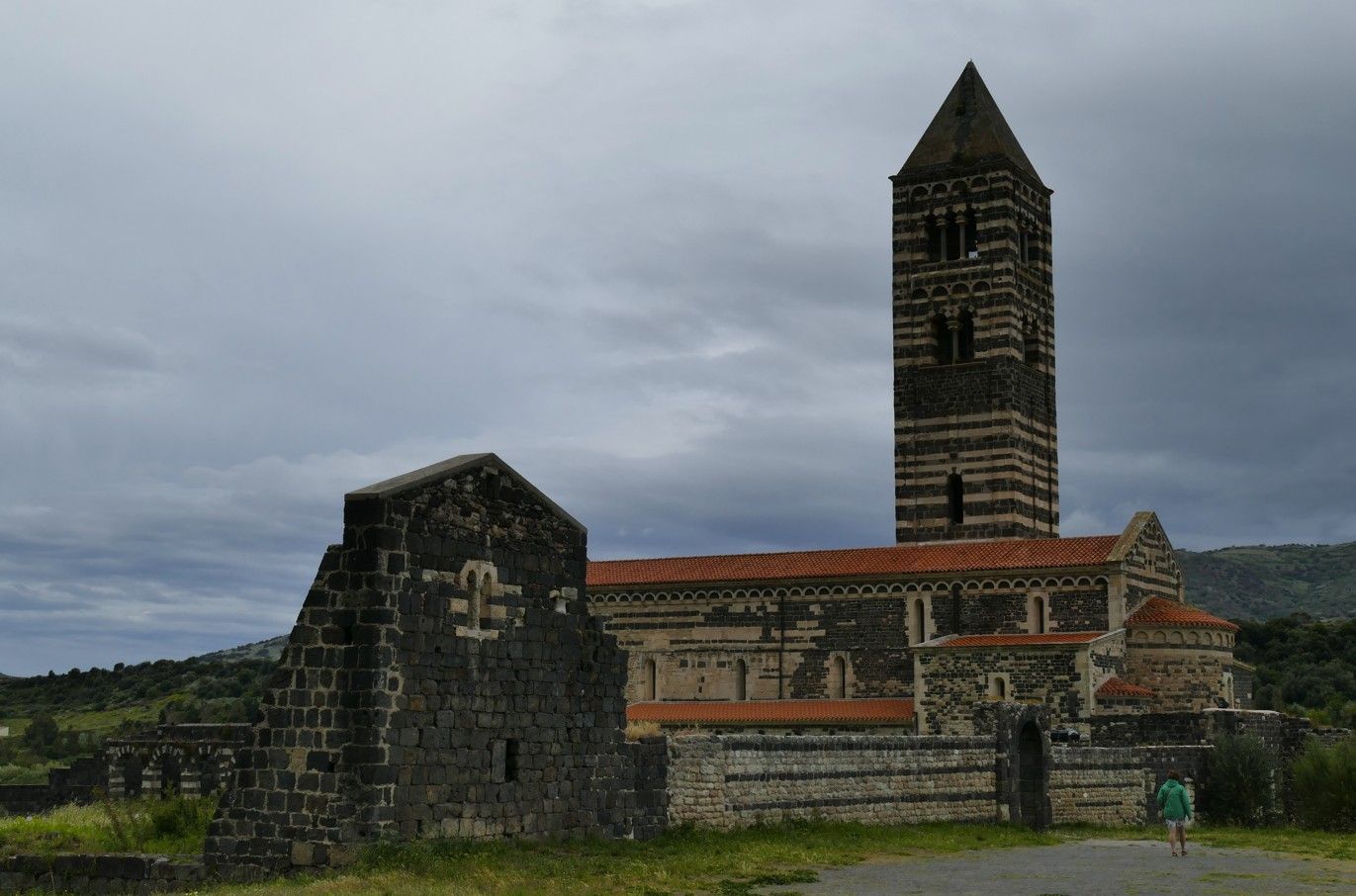 Middeleeuwse kerk met hoge, gestreepte klokkentoren onder een bewolkte hemel.