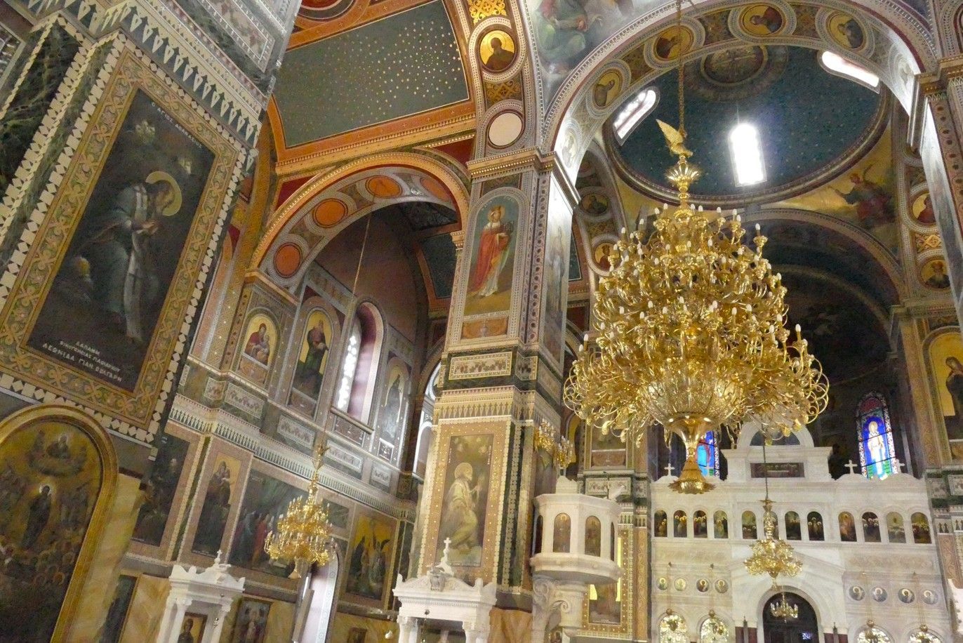 Een rijk versierd interieur van een kerk met gouden kroonluchters, gewelfde plafonds en religieuze schilderijen.