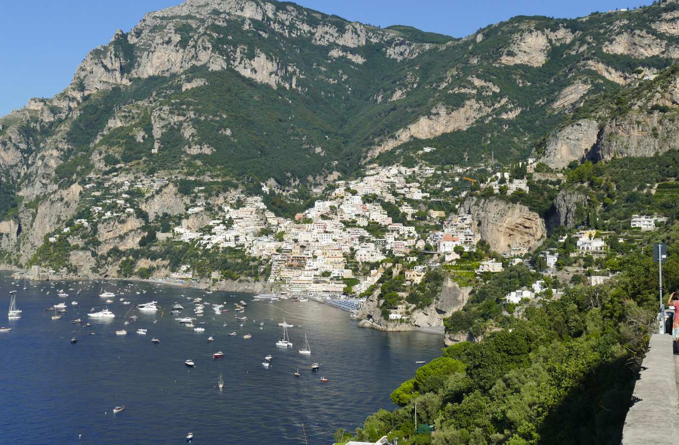 Het Italiaanse kustplaatsje Positano, gelegen tegen een berghelling, met witte gebouwen, boten en blauw water.