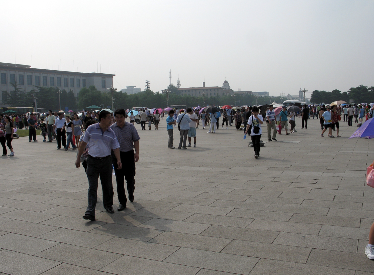 Mensen lopen over het Tiananmenplein in Peking. Gebouwen op de achtergrond; zonnige dag.