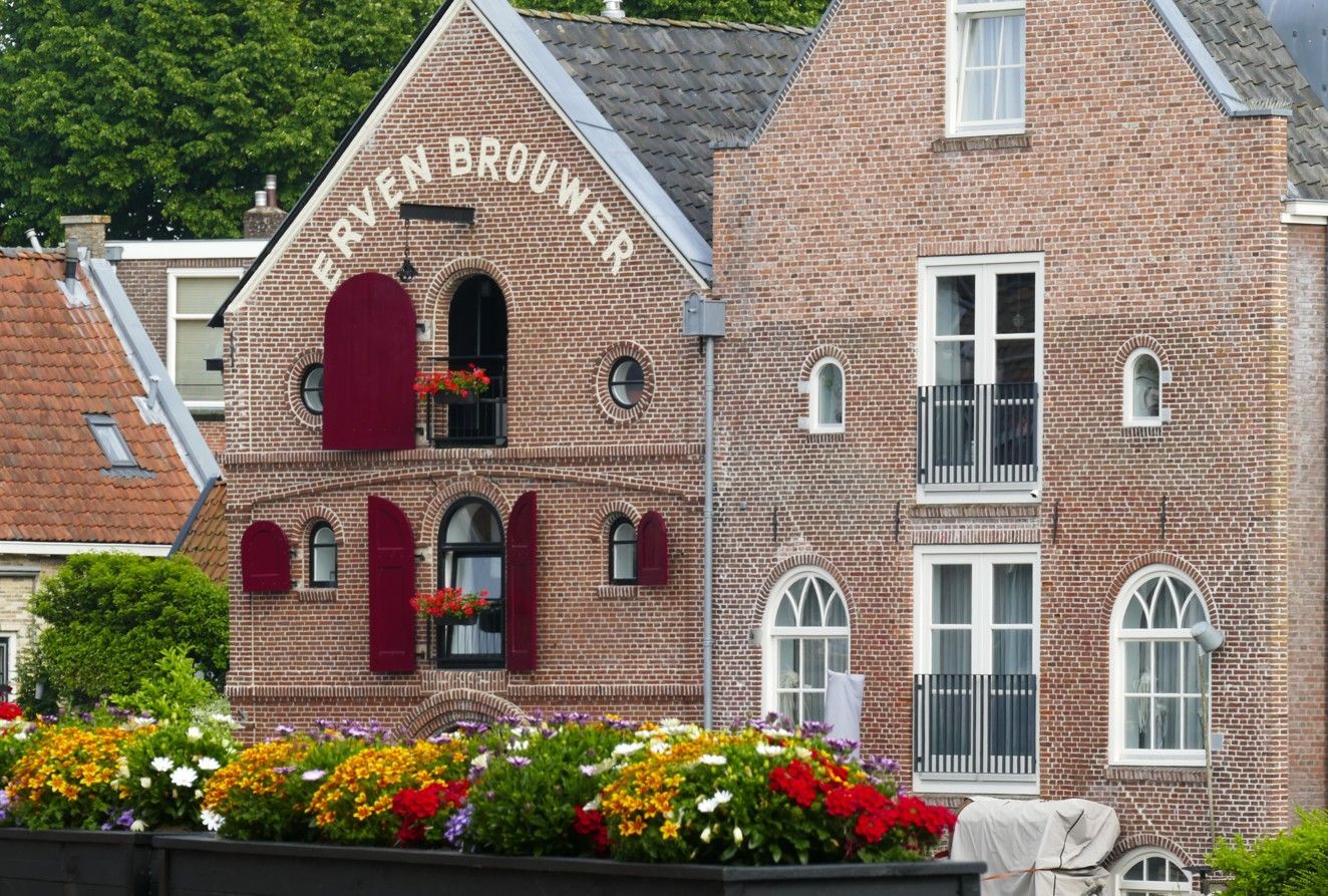Bakstenen gebouwen met rode accenten, bloembakken en de tekst 