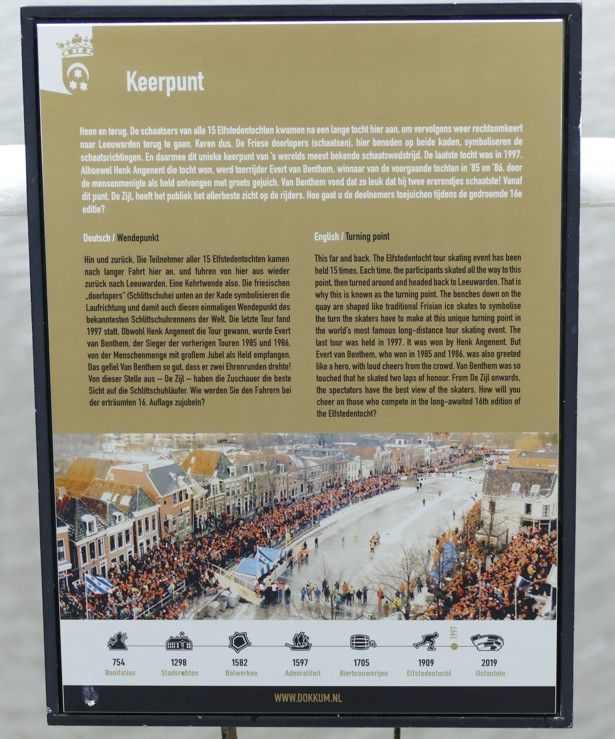 Bord over Koerpunt: een historische processie met veel mensen langs de straat.