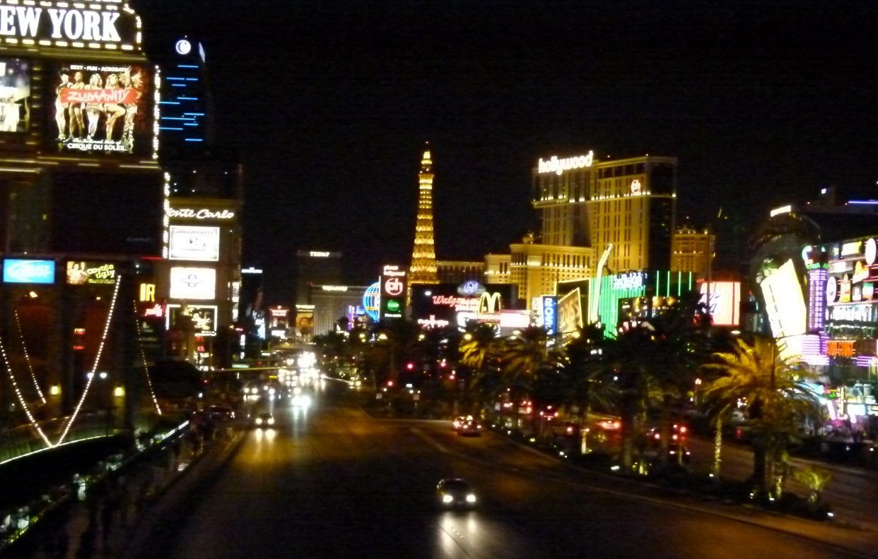Nachtzicht op de Las Vegas Strip met verlichte casino's, straatlantaarns en de replica van de Eiffeltoren.