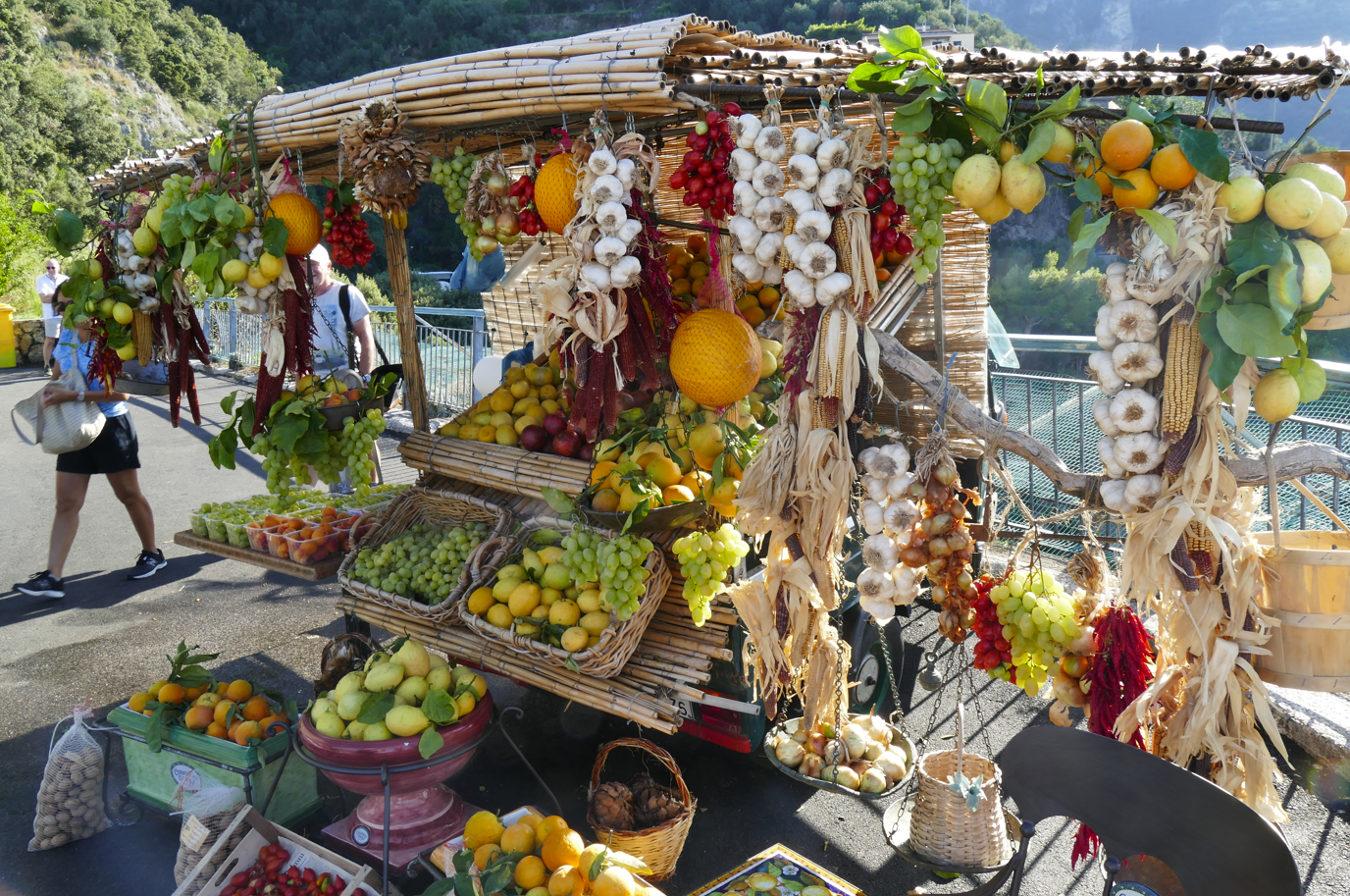 Een groente- en fruitkraam langs de weg, met citroenen, tomaten, knoflook en andere producten.