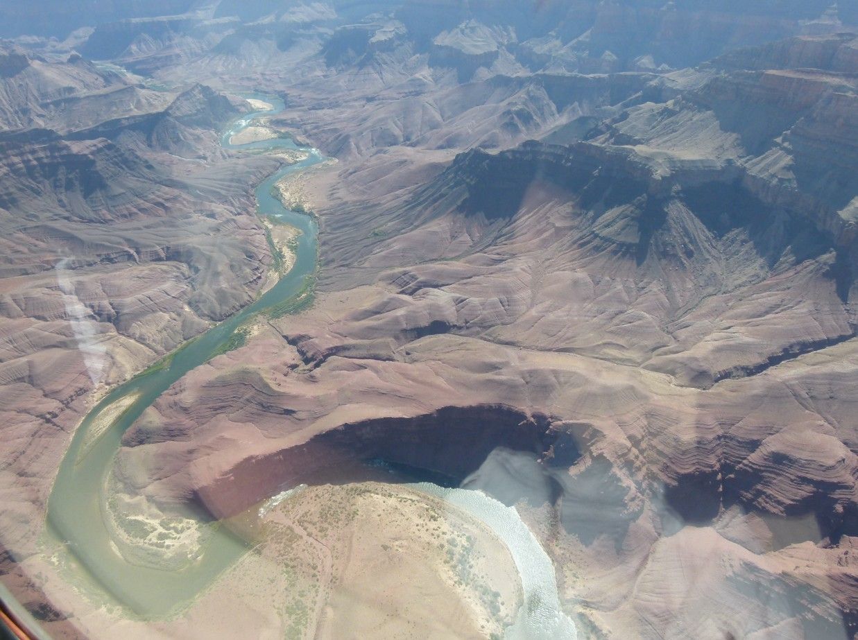 Luchtfoto van een kloof met een rivier die erdoorheen kronkelt; een dor, bruin landschap.