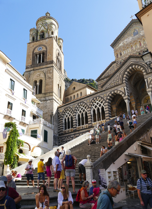 Mensen op de trappen die leiden naar een kathedraal en toren in Amalfi, Italië.