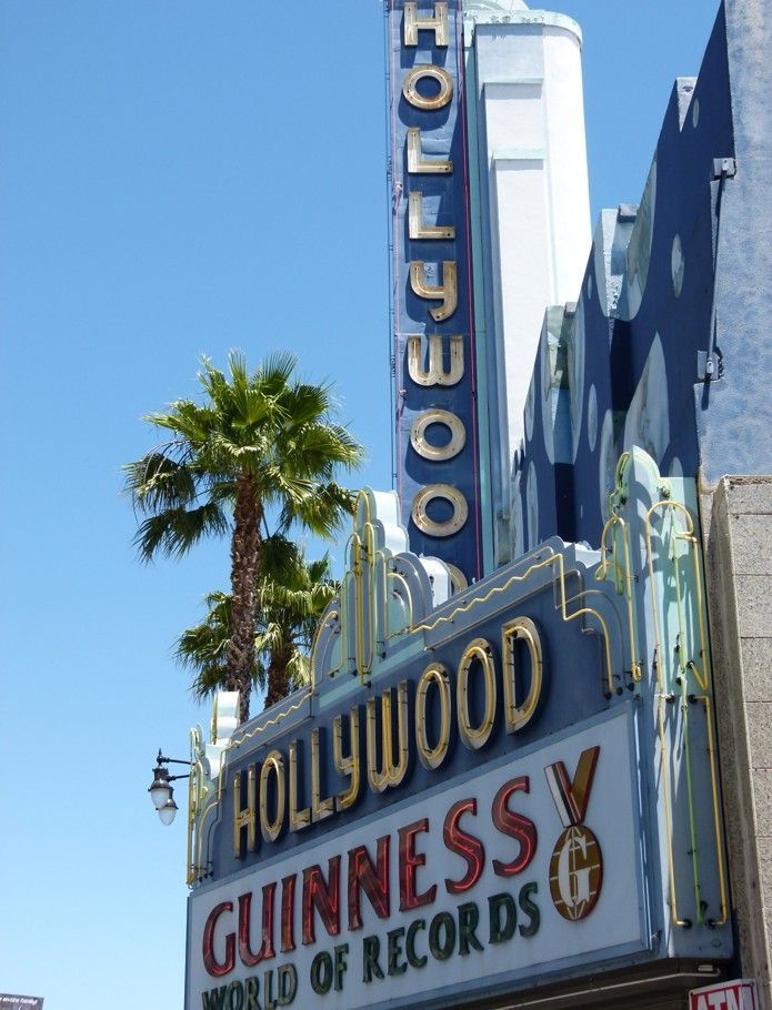 Het Hollywood Guinness World Records-gebouw met het blauw-gouden bord, palmbomen en een heldere hemel.