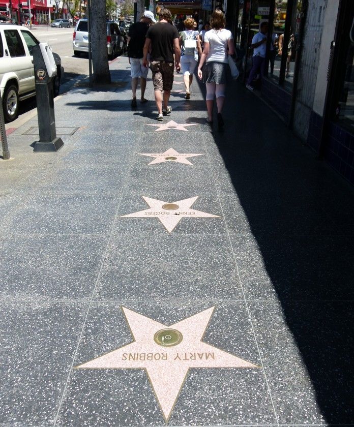 Sterren van de Hollywood Walk of Fame op een stoep, met mensen die op de achtergrond lopen.