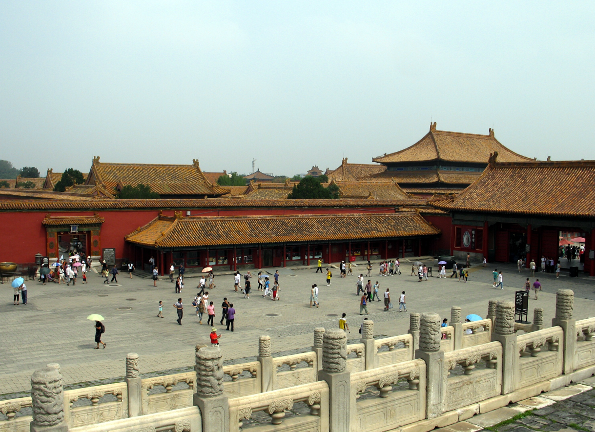 Binnenplaats van de Verboden Stad, Peking, China. Rode muren en gouden daken, veel mensen, bewolkte lucht.