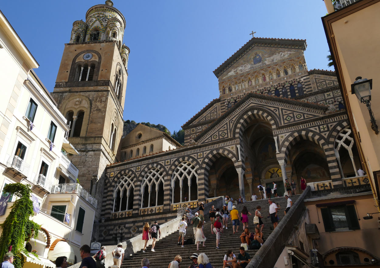 Kathedraal van Amalfi, Italië, met gedetailleerde gevel en trappen ernaartoe; mensen zichtbaar.