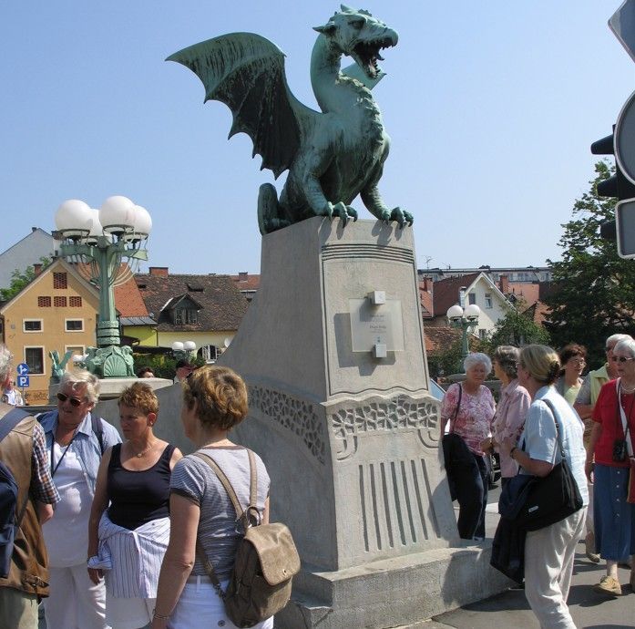 Drakenbeeld op een brug in Ljubljana, Slovenië, met toeristen. De bronzen draak heeft zijn vleugels uitgespreid.