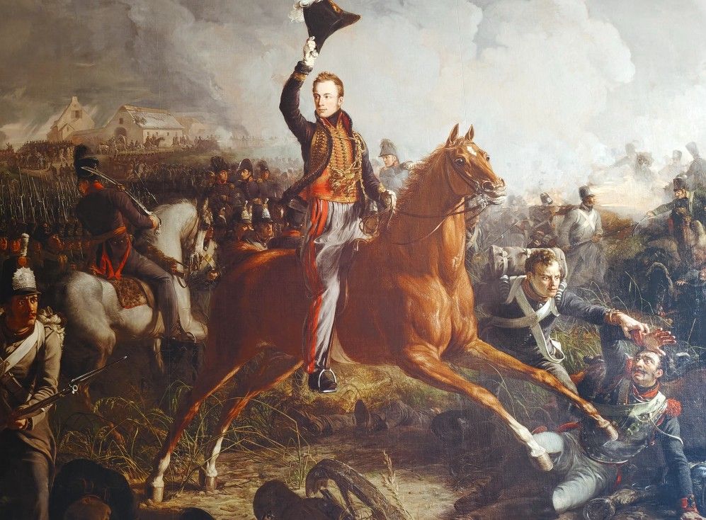 Een man te paard neemt zijn hoed af op een slagveld, omringd door soldaten en gevechten.