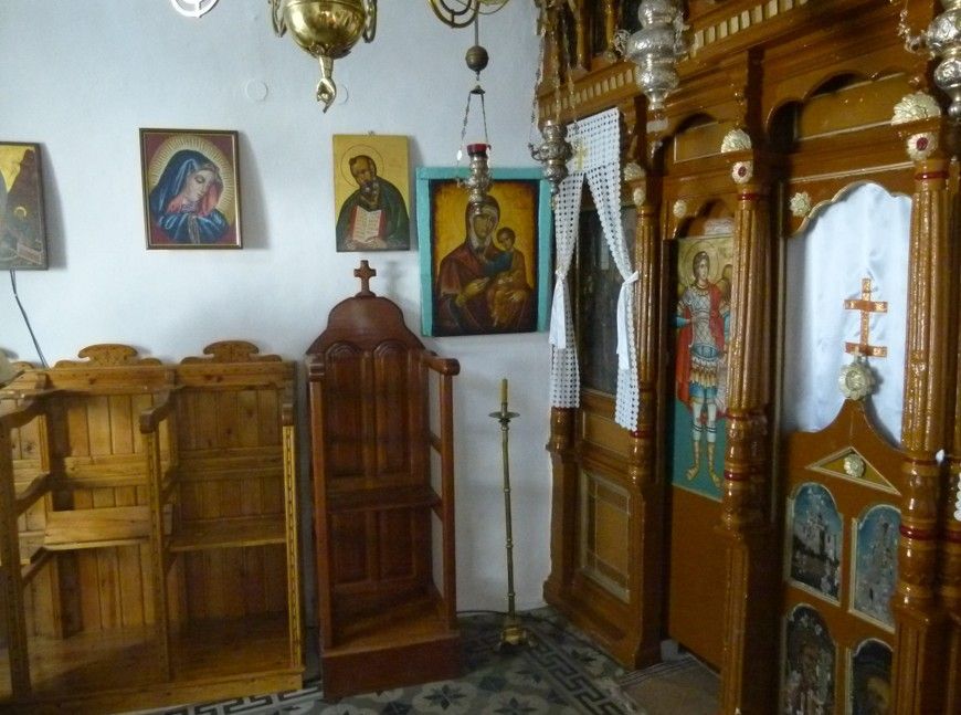 Interieur van een houten orthodoxe kerk met iconen, een biechtstoel en sierlijke altaardeuren.