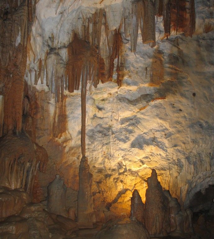 Het interieur van de grot wordt verlicht door warm licht, met stalactieten en stalagmieten goed zichtbaar.