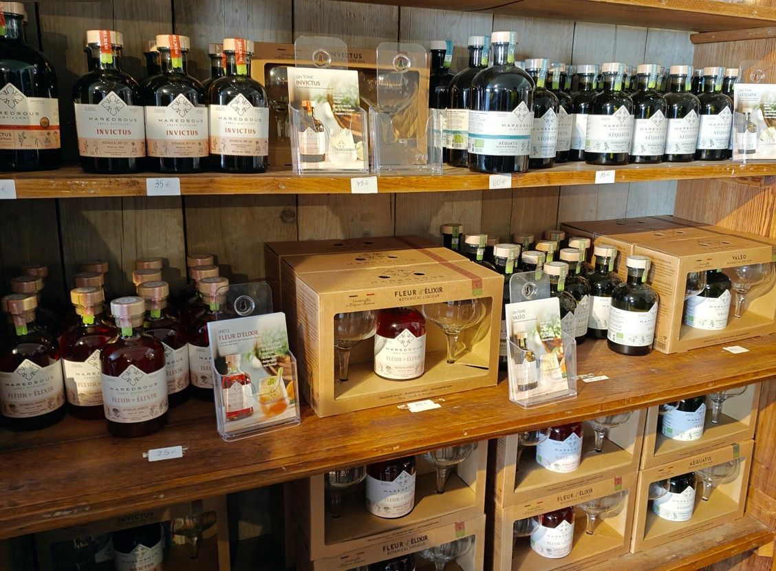 Schappen in een winkel met diverse flessen sterke drank en geschenksets met glazen flessen en kartonnen verpakkingen.